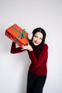 woman in red long sleeve shirt holding red gift box